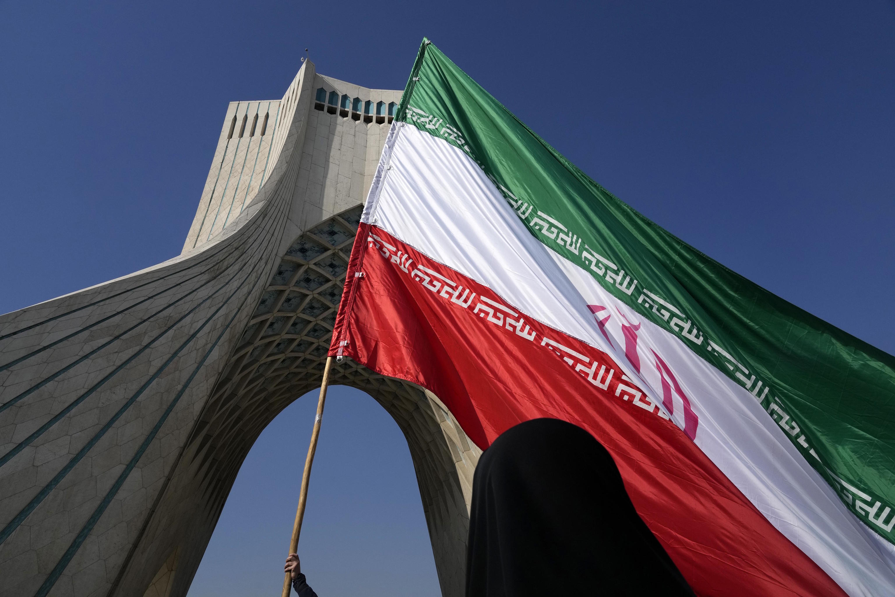 A huge Iranian flag is carried under the Azadi (Freedom) monument tower.