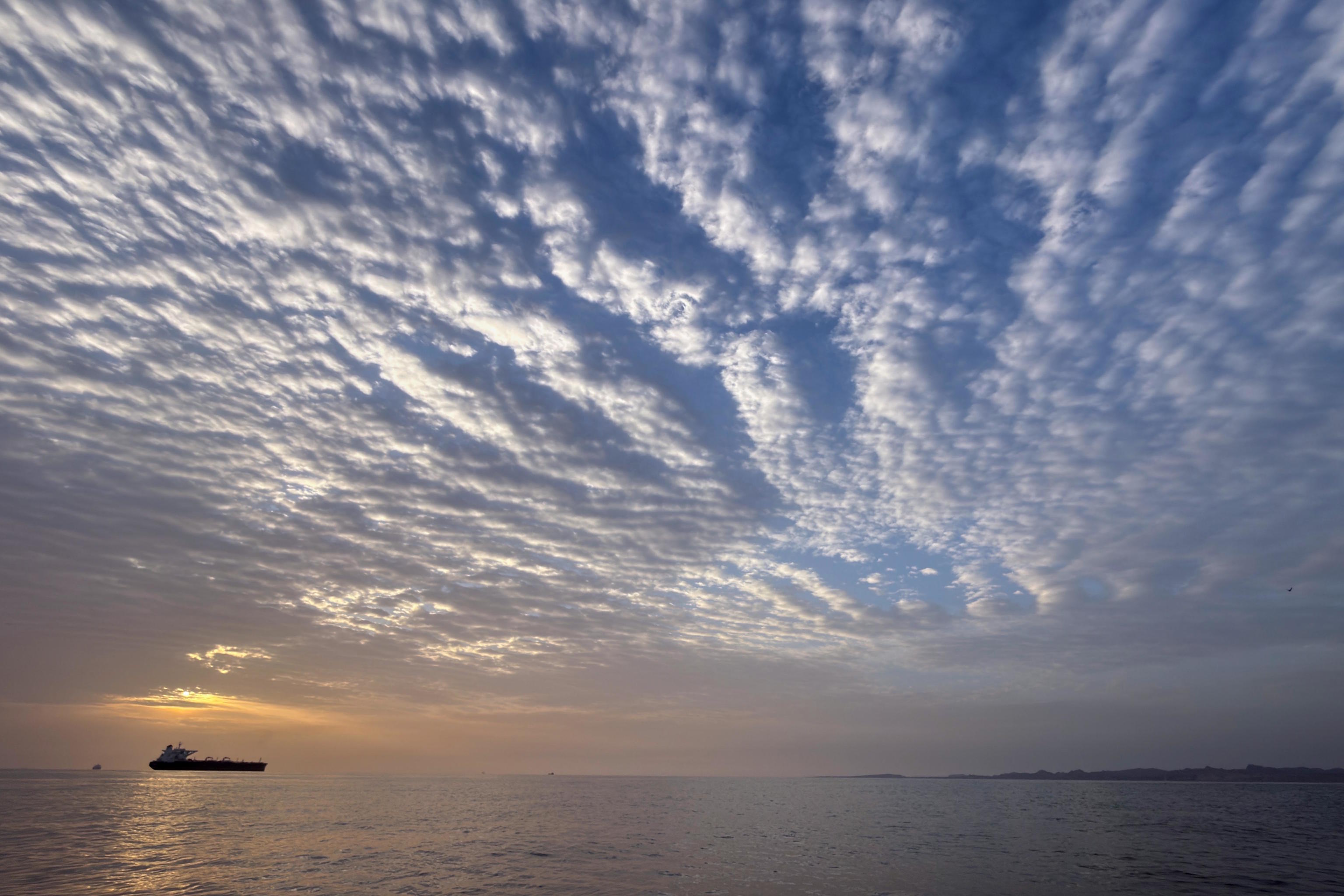 The sun rises behind a tanker anchored in the Strait of Hormuz.