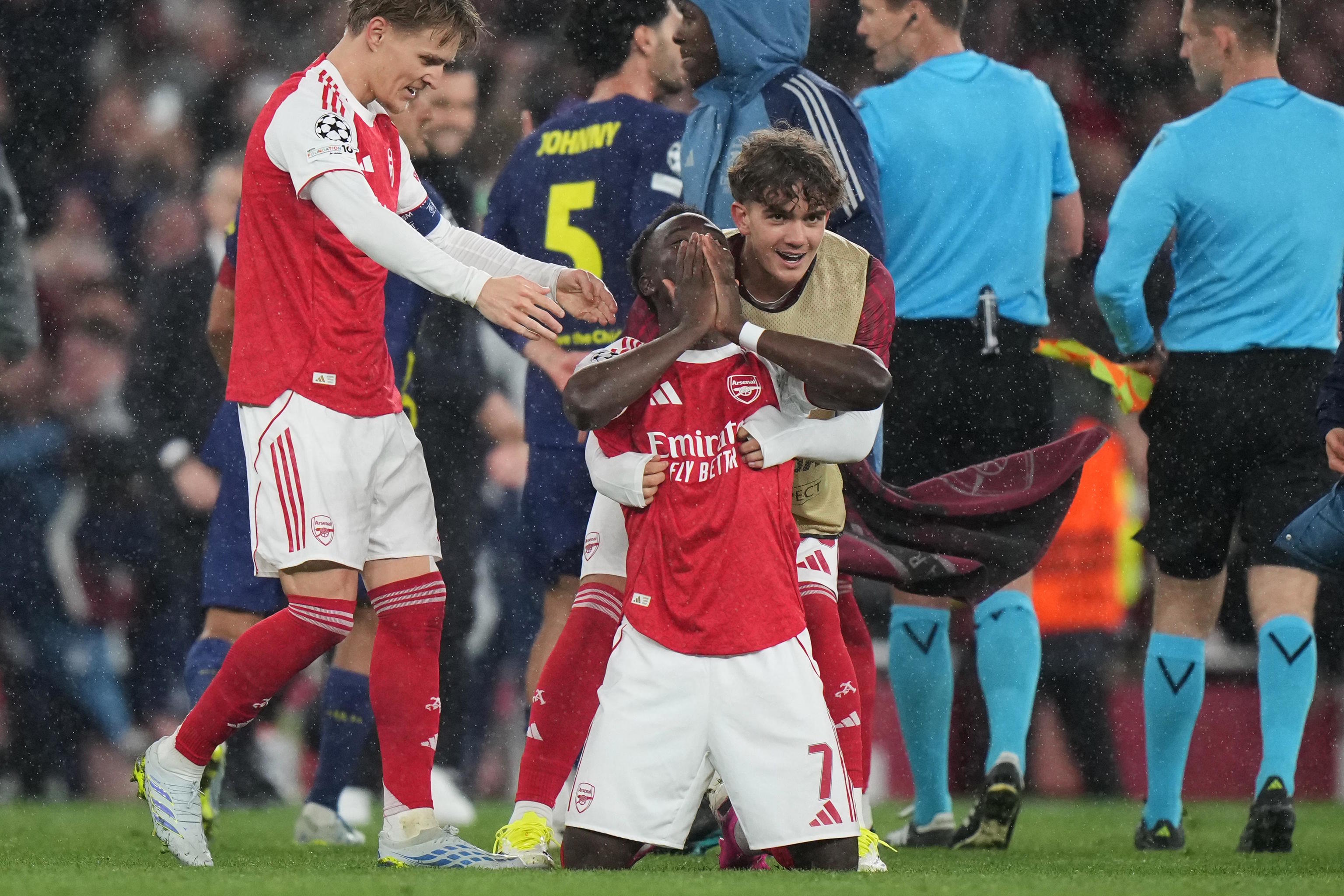 Arsenal's Bukayo Saka kneels on the ground celebrating.