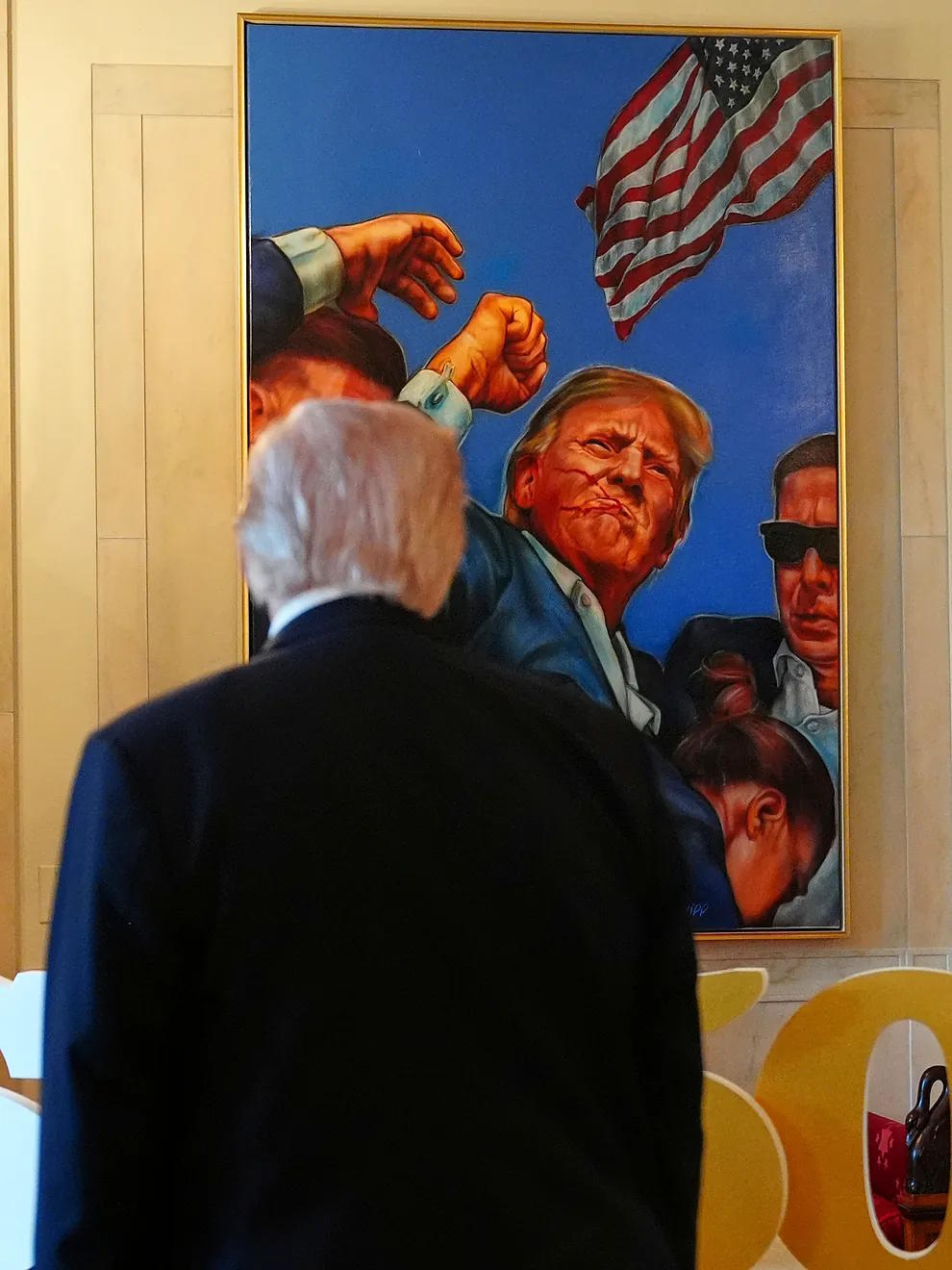 Donald Trump looks at a painting representing him.