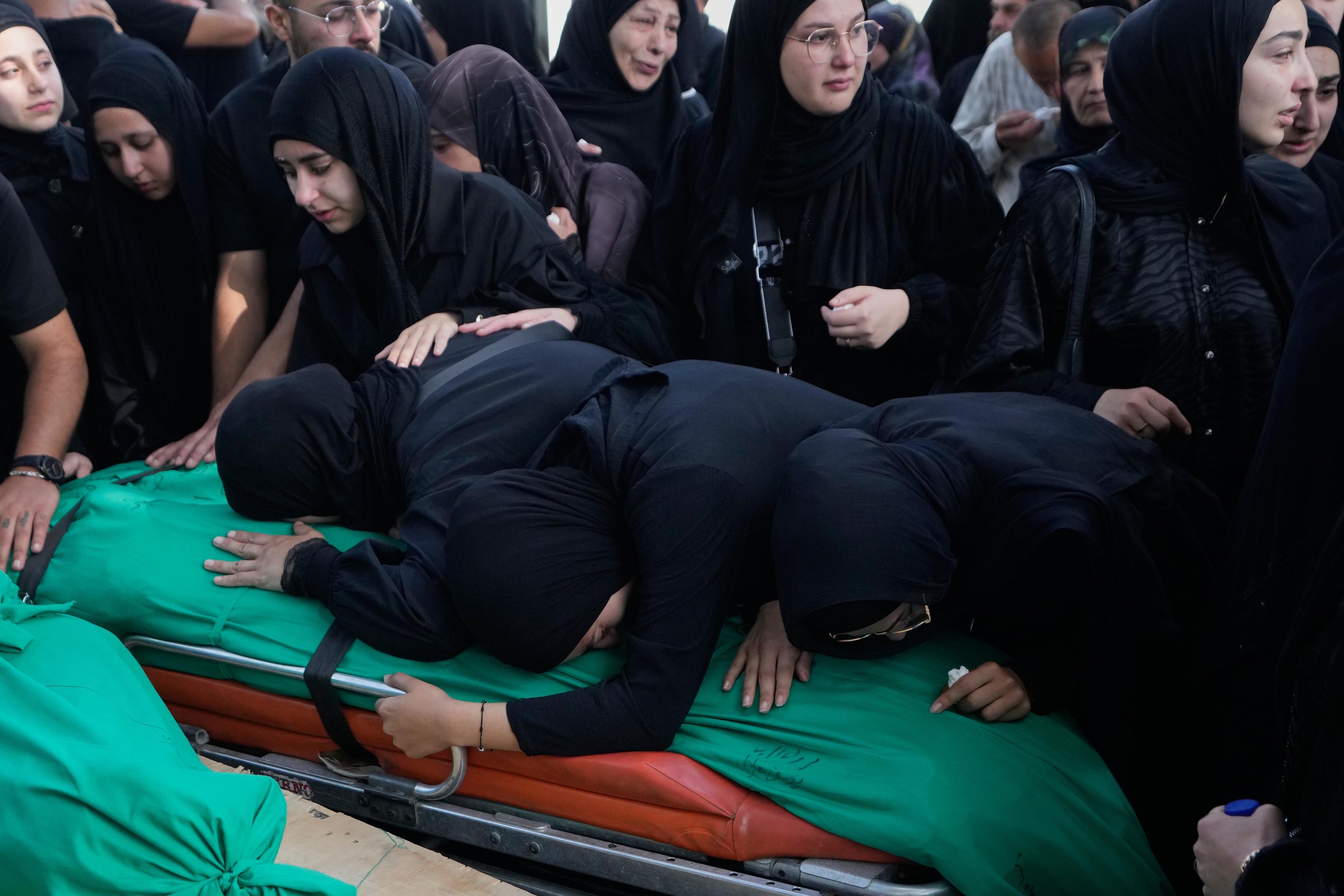 Mourners grieve over the bodies of people killed in an Israeli airstrike in the village of Saksakieh.