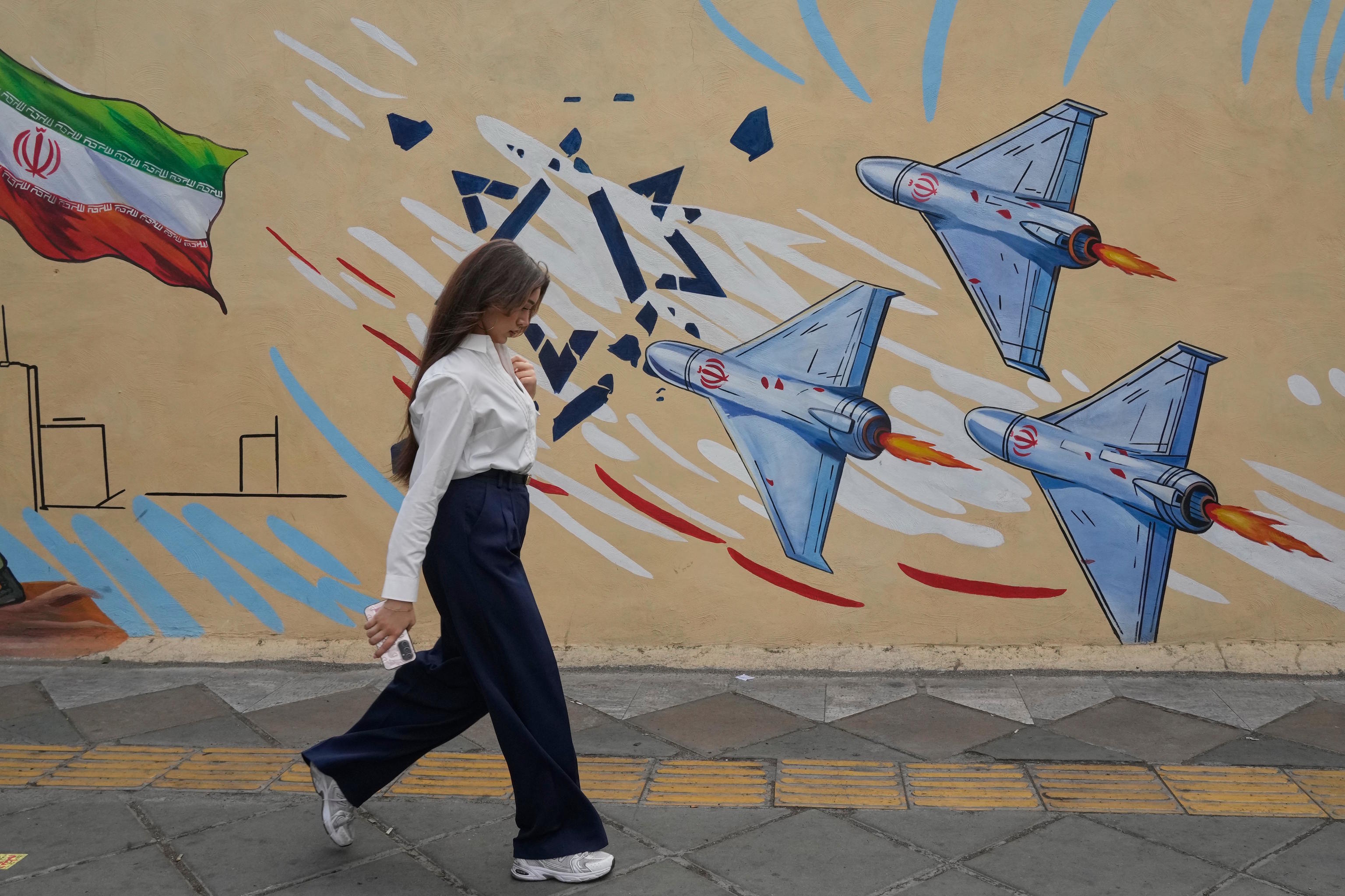 Iranian girl walks without veils past an anti-Israel mural in Tehran.