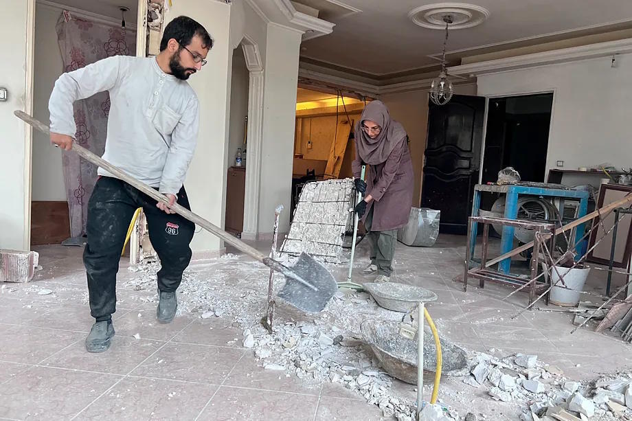 An Iranian man and woman work on rebuilding a home.