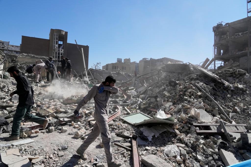 Several men inspect the ruins of a police station during the US-Israeli campaign of attacks in Tehran
