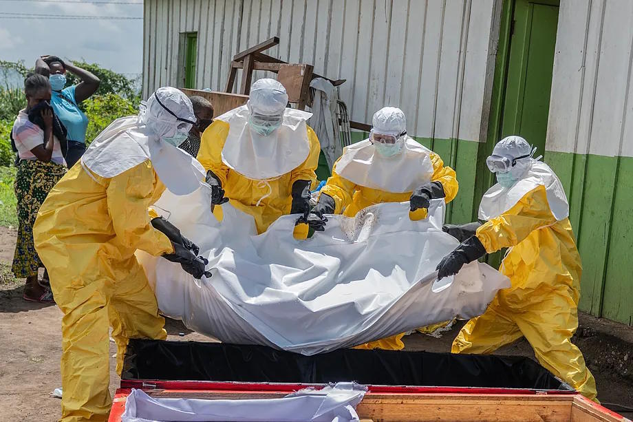 Red Cross workers place the body of an Ebola victim in a coffin at a health center in Rwampara, Democratic Republic of the Congo.
