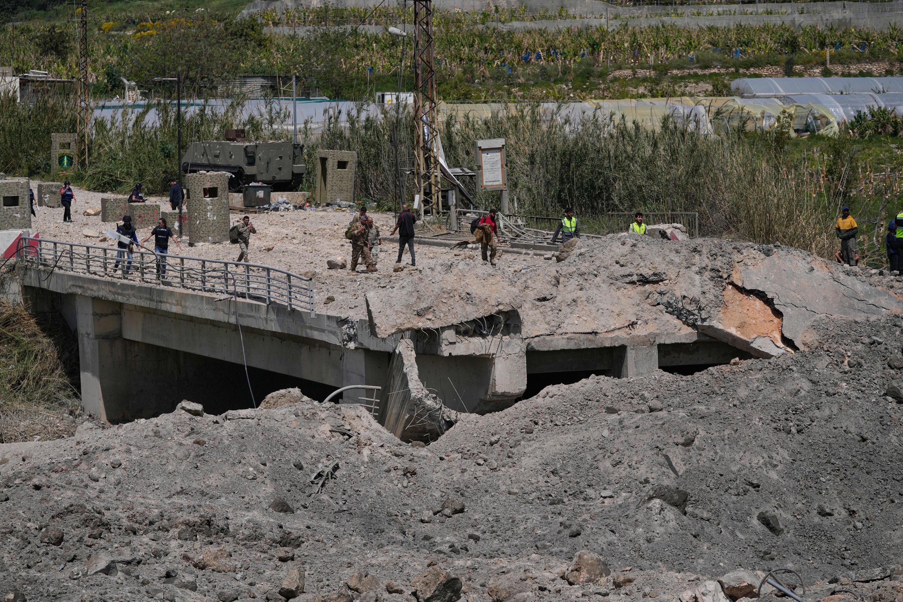 Lebanese soldiers and civilians cross on foot through a destroyed bridge that was hit in an Israeli airstrike.