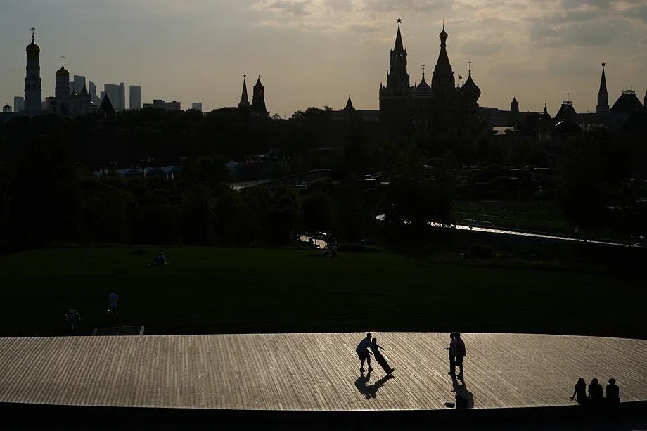 People stroll through Zaryadye Park, with the Kremlin in the background, on a hot day in Moscow.
