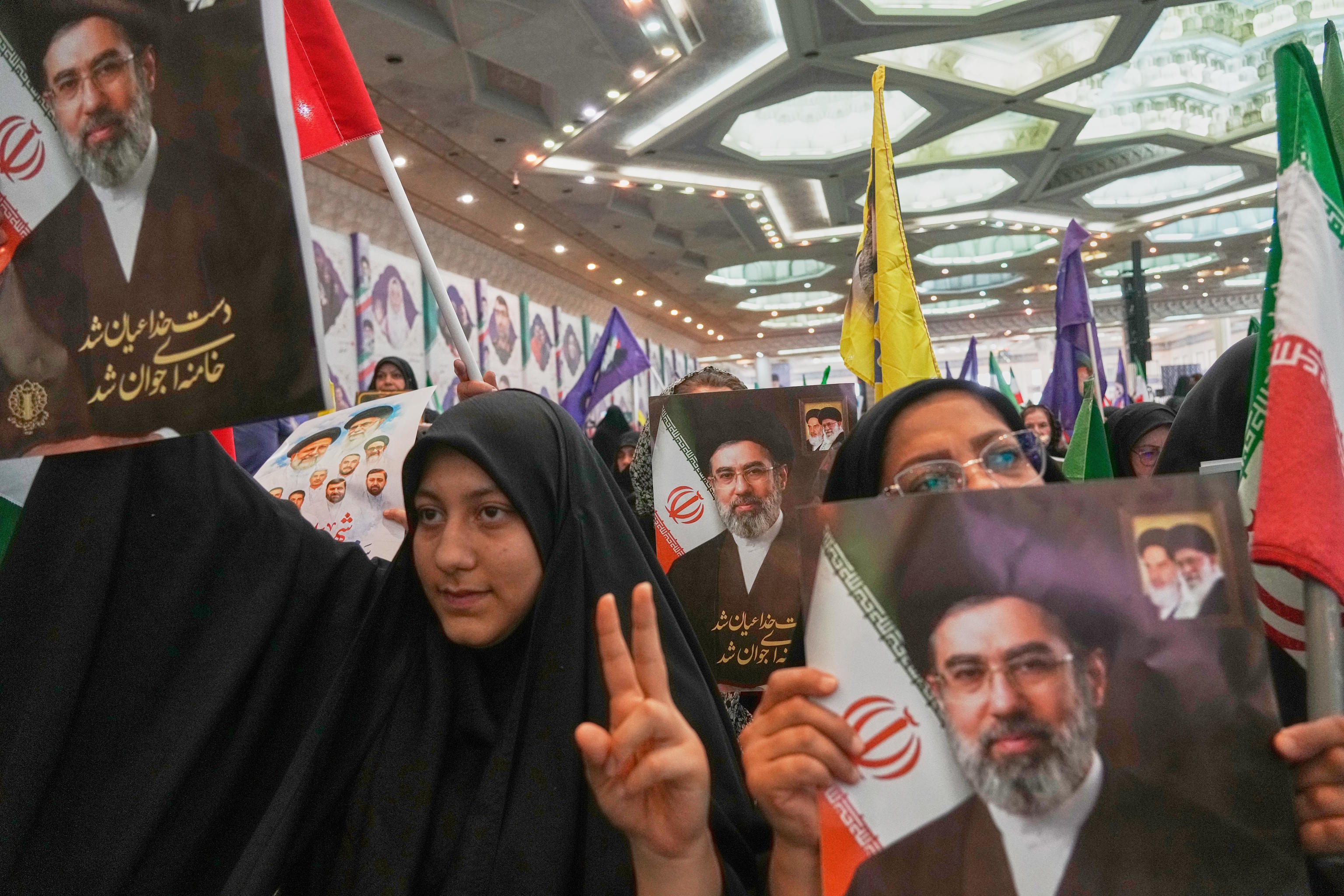 Women hold portraits of Iran's Supreme Leader, Mojtaba Jamenei.