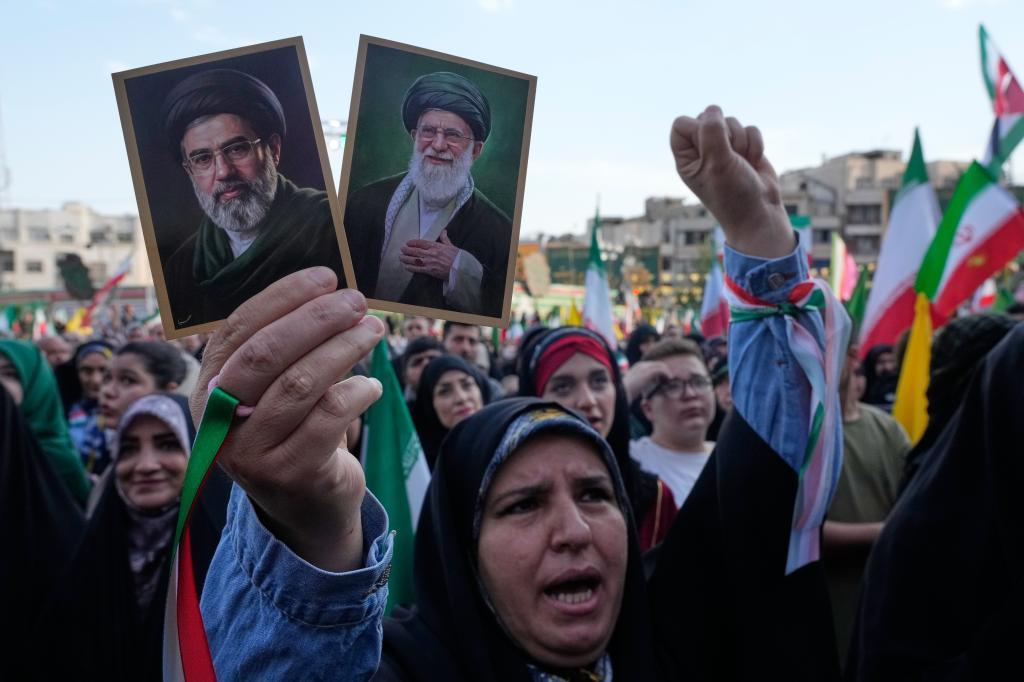 A woman holds pictures of Iran's Supreme Leader, Ayatollah Mojtaba Khamenei (left), and his father, the late Ali Khamenei