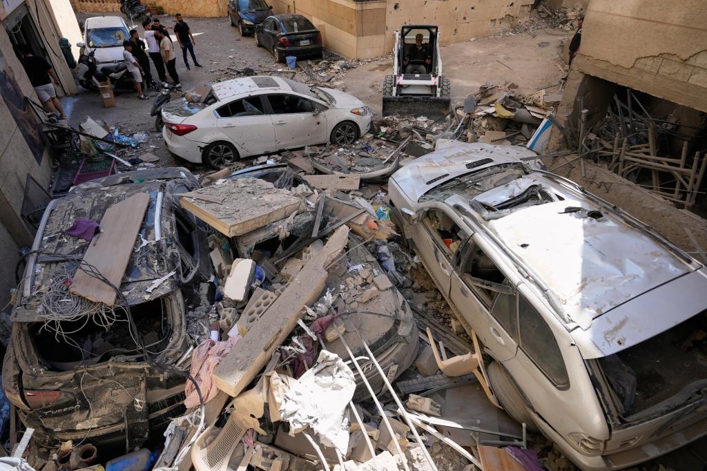 A worker uses a skid loader as he removes rubble at the site of a destroyed apartment that was hit in an Israeli airstrike in Choueifat town,