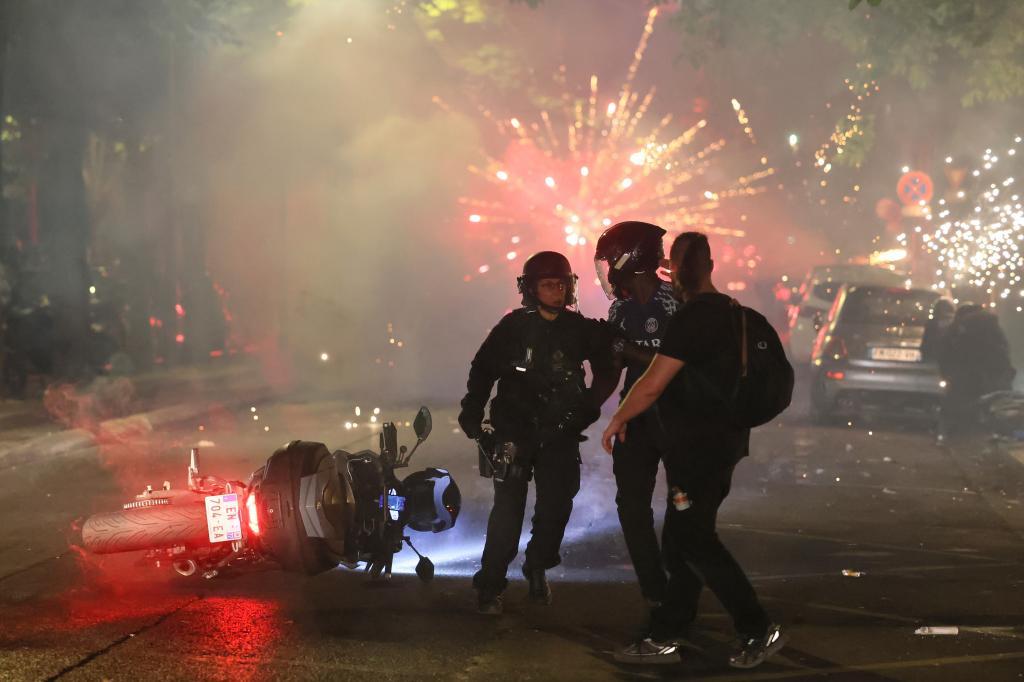 Police try to disperses PSG supporters who left off fireworks as they celebrate in Paris,