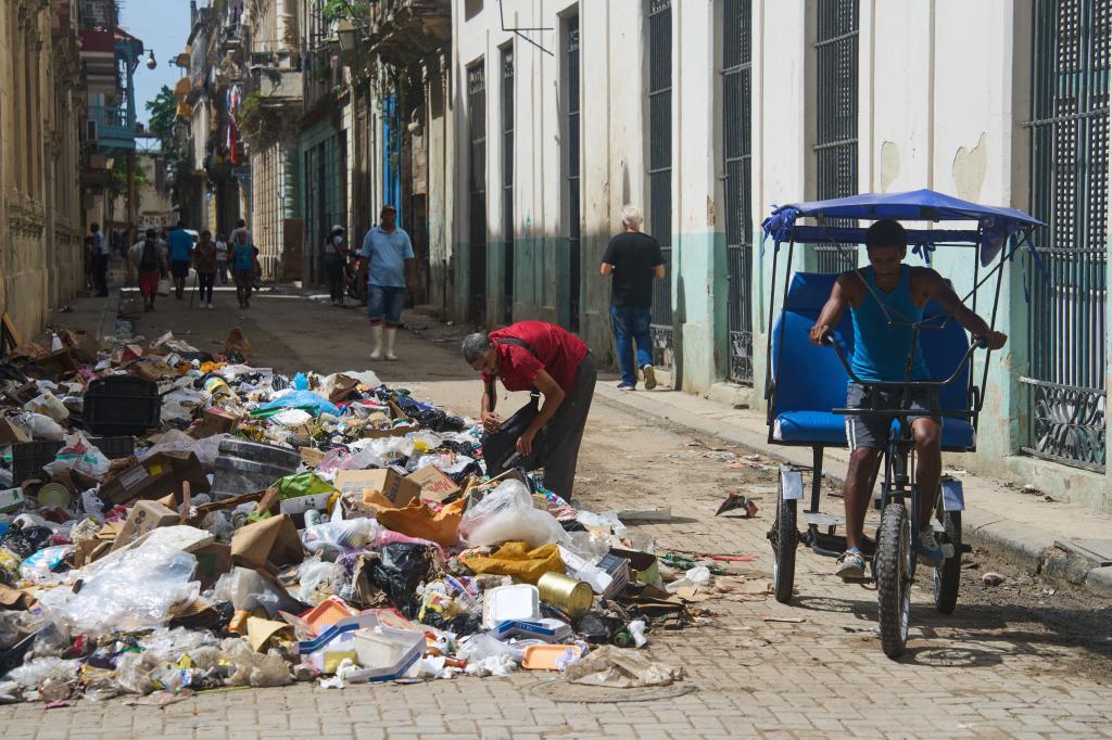 A man searches through a pile of trash for items to salvage in Havana, Cuba