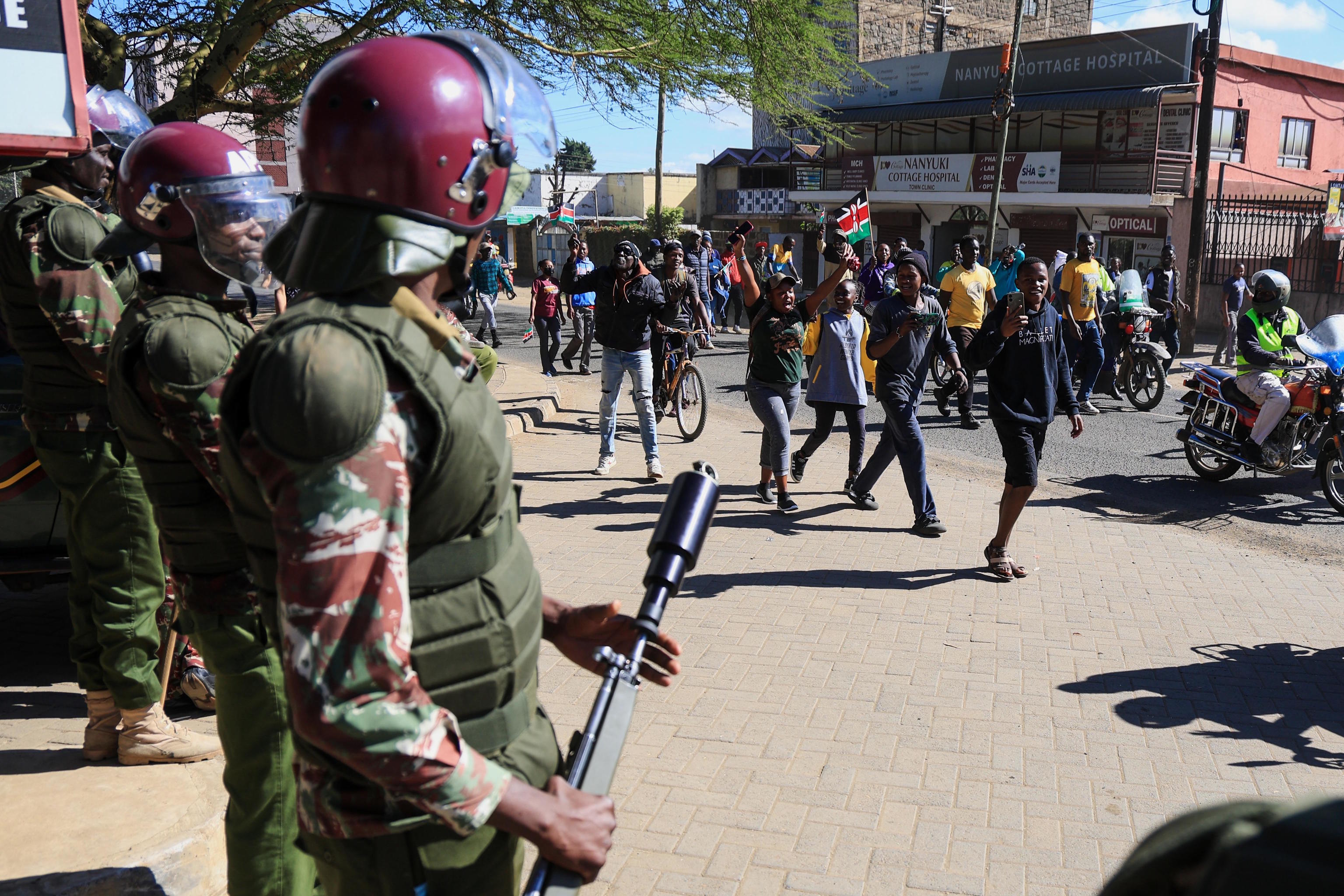 Anti-riot police officers stand by as demonstrators protest against a Ebola quarantine center.