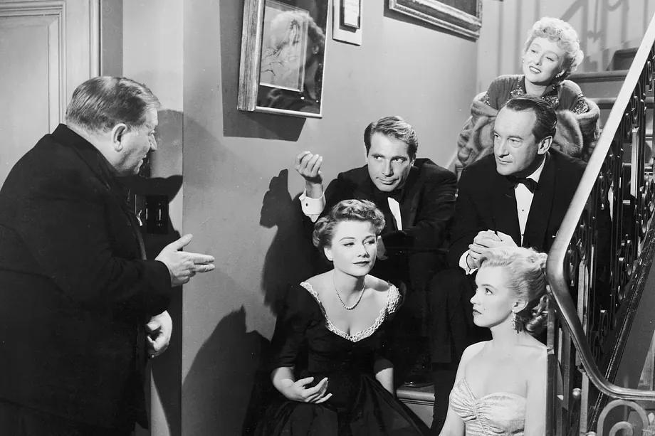 Scene from All About Eve. At the top of the stairs, Celeste Holm; Marilyn Monroe below in a light dress.