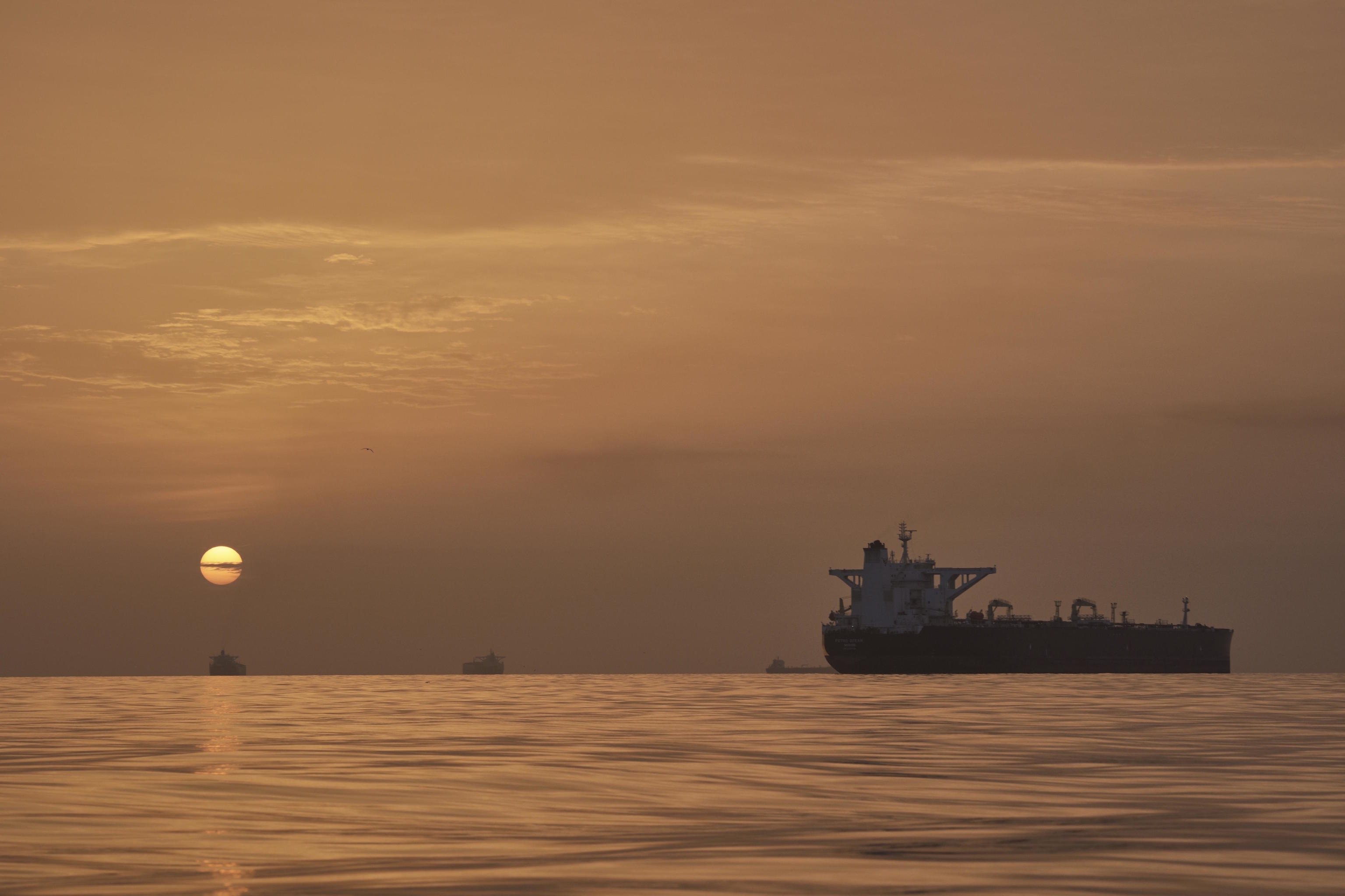 The sun rises behind tankers anchored in the Strait of Hormuz off the coast of Qeshm Island.