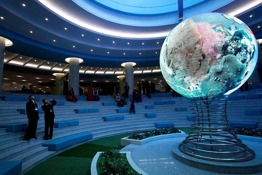 Two people look at a digital sphere in Seoul.