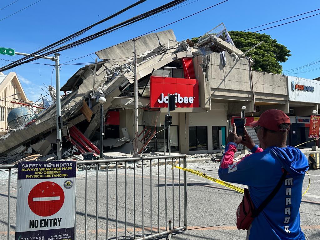 Residents takes a picture of a collapsed structure following an earthrquake