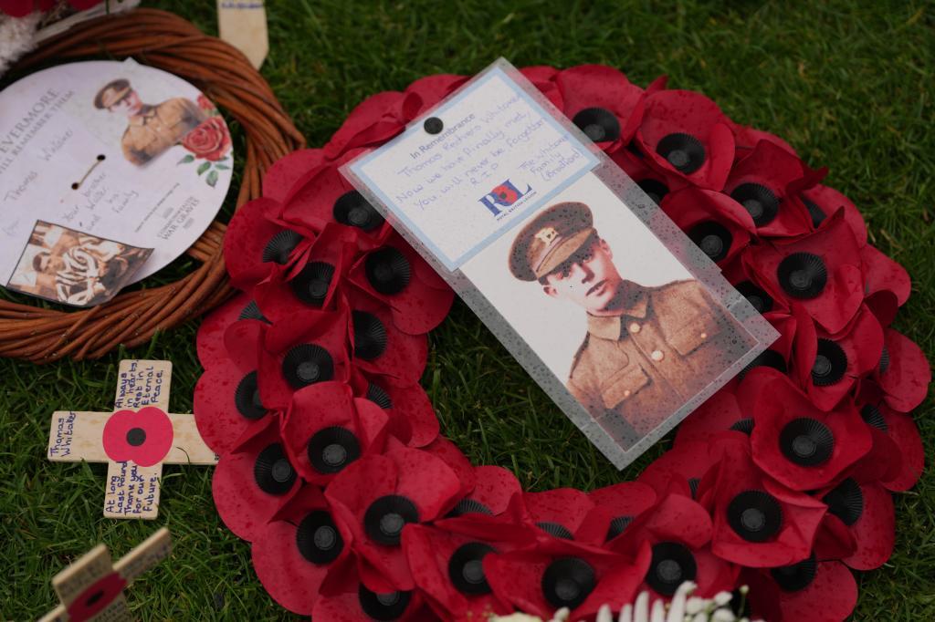 A poppy wreath and a photo next to the grave of Private Thomas Redvers Whitaker during a burial ceremony for six British soldiers of World War I