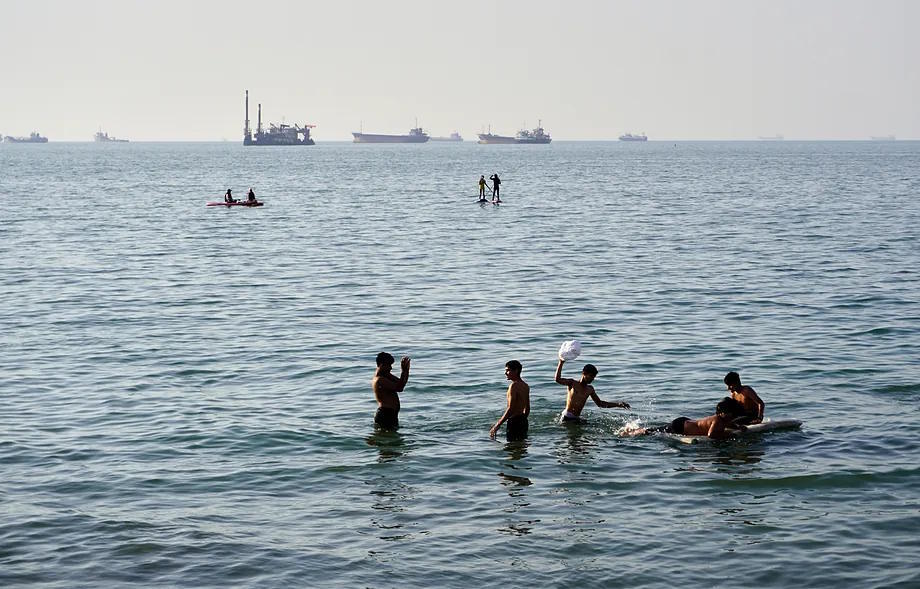 Several residents swim and play in the waters of the Strait of Hormuz.