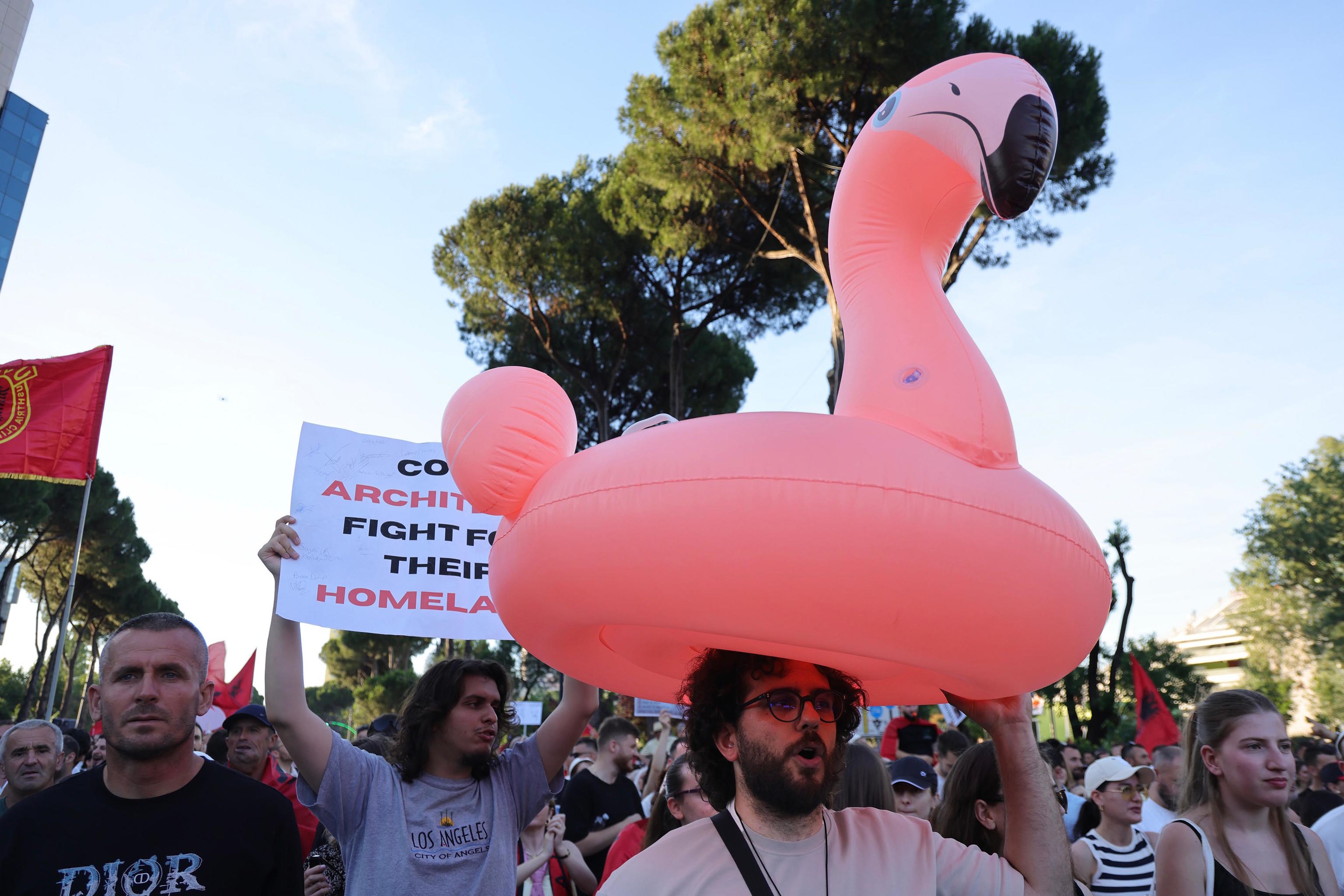 A protester carries a flamingo pool float during a rally in Tirana.