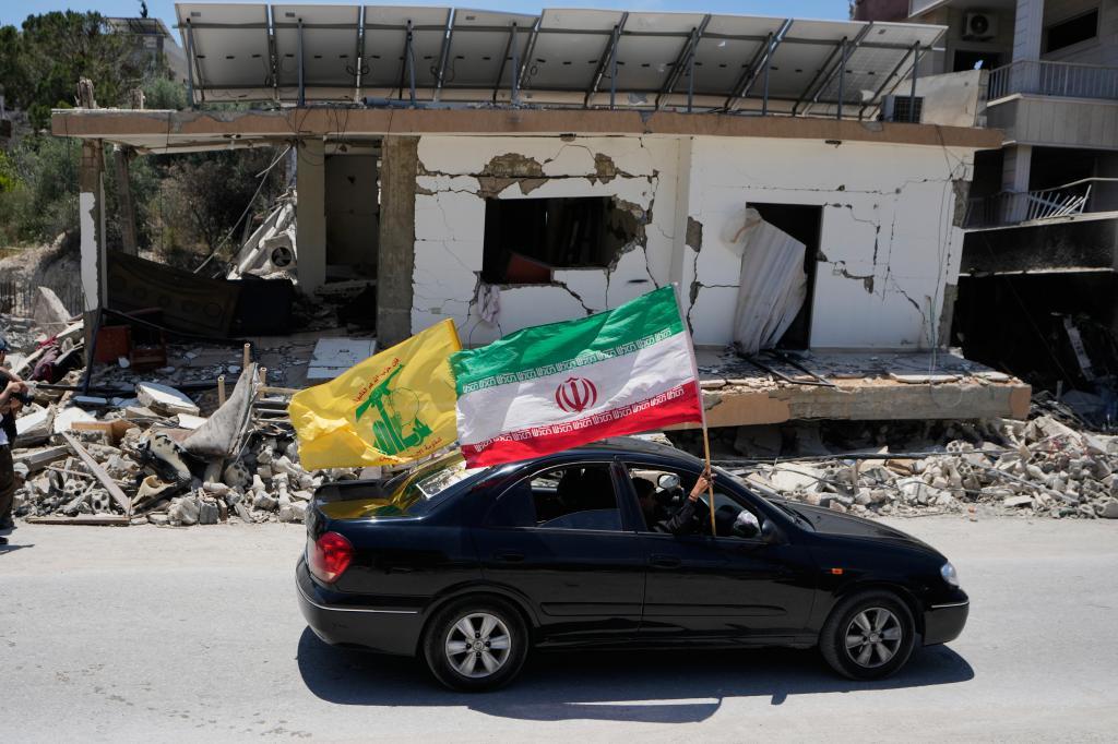 Displaced residents hold an Iranian and a Hezbollah flags