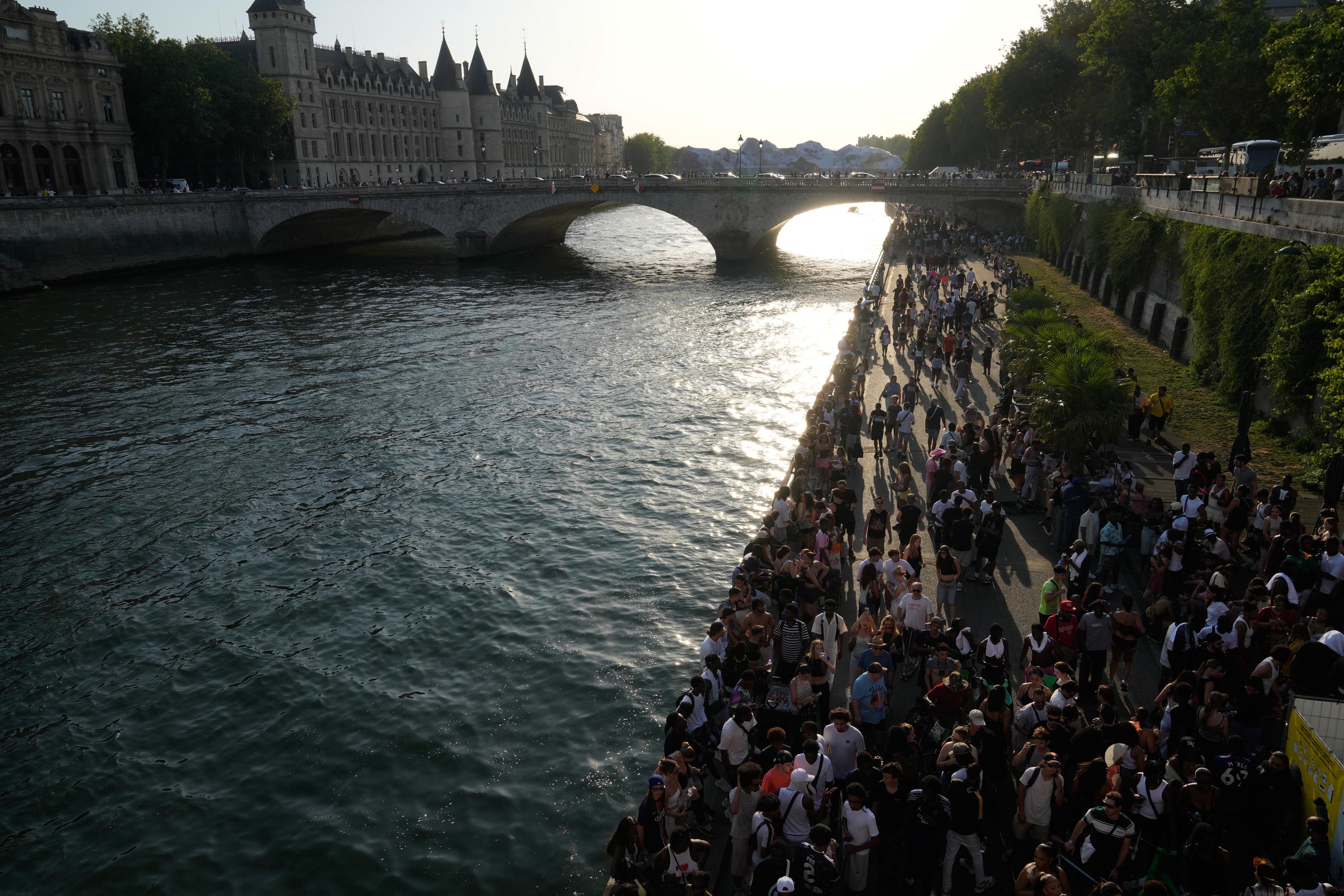 People walk along the Seine river.