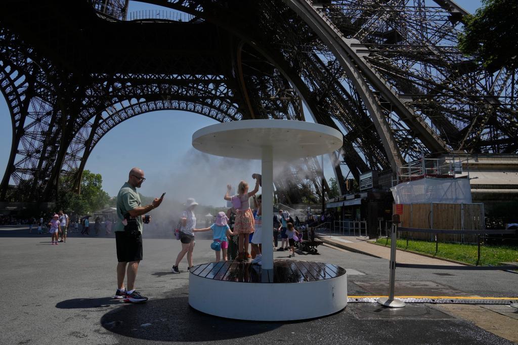 People cool off from the intense heat at a temporary fountain placed under the Eiffel Tower