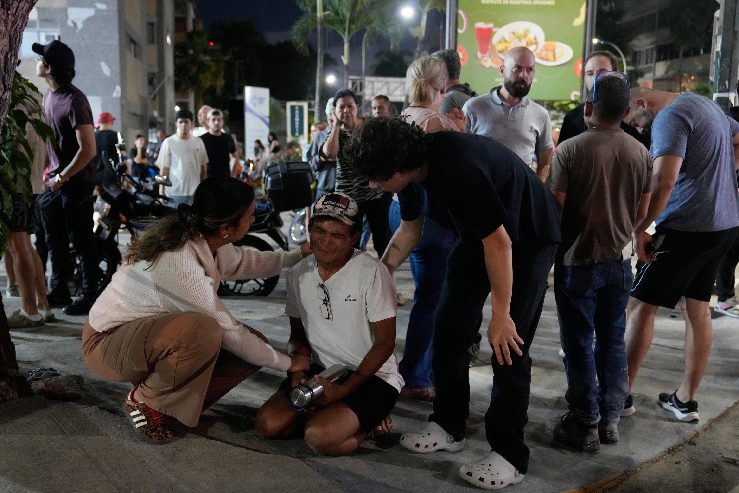 People comfort a man in Caracas.