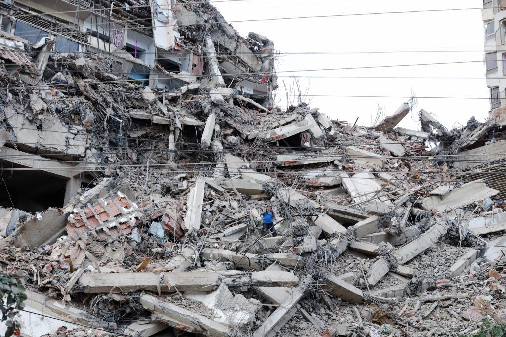 A man walks among the rubble of a building that collapsed in earthquakes the previous day in La Guaira, Venezuela