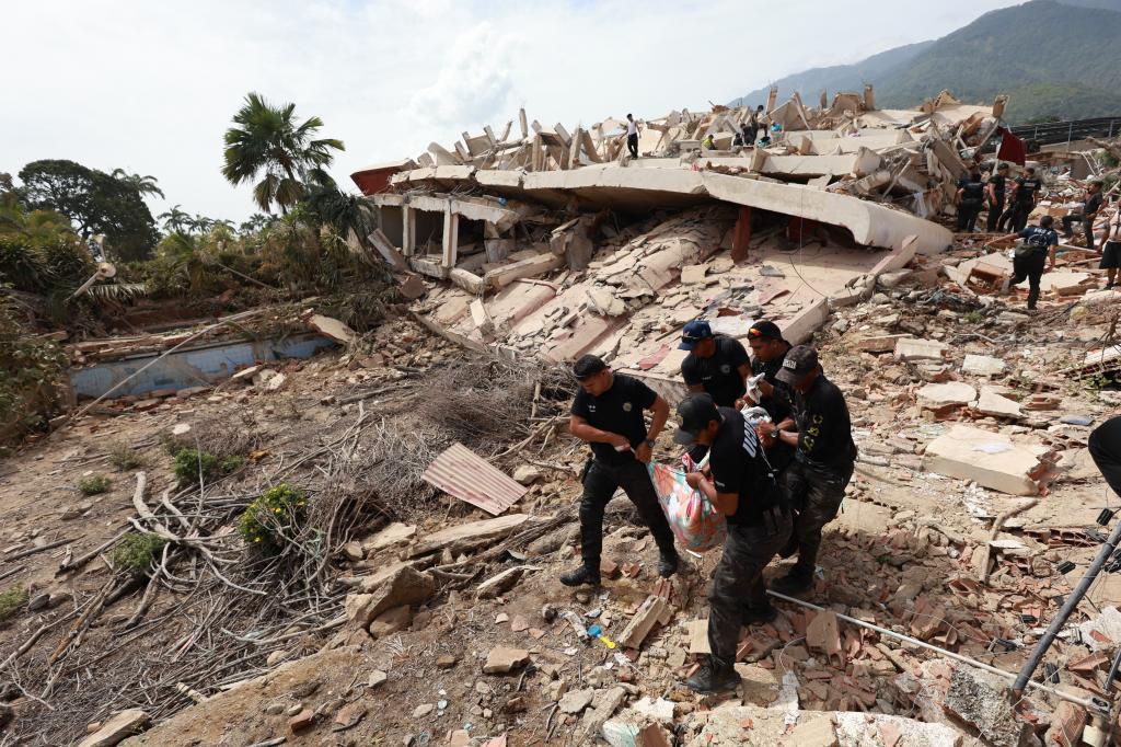 Police carry a body from a building that collapsed after earthquakes struck in La Guaira,