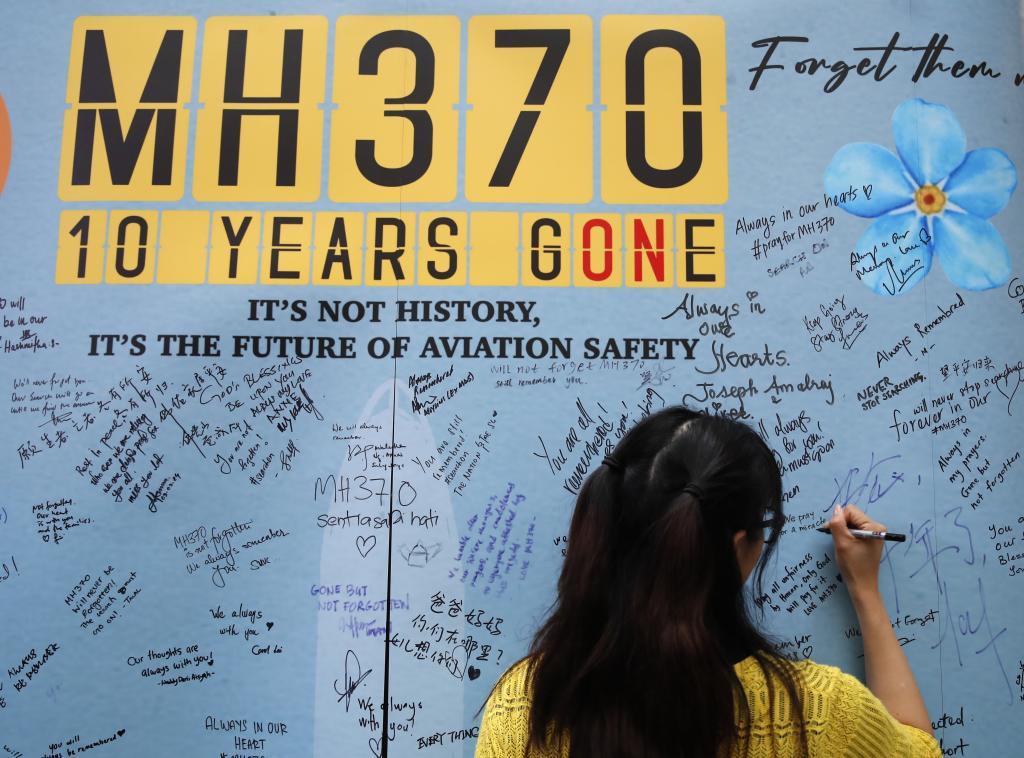 A woman writes well messages on a message board during the tenth annual remembrance event at a shopping mall