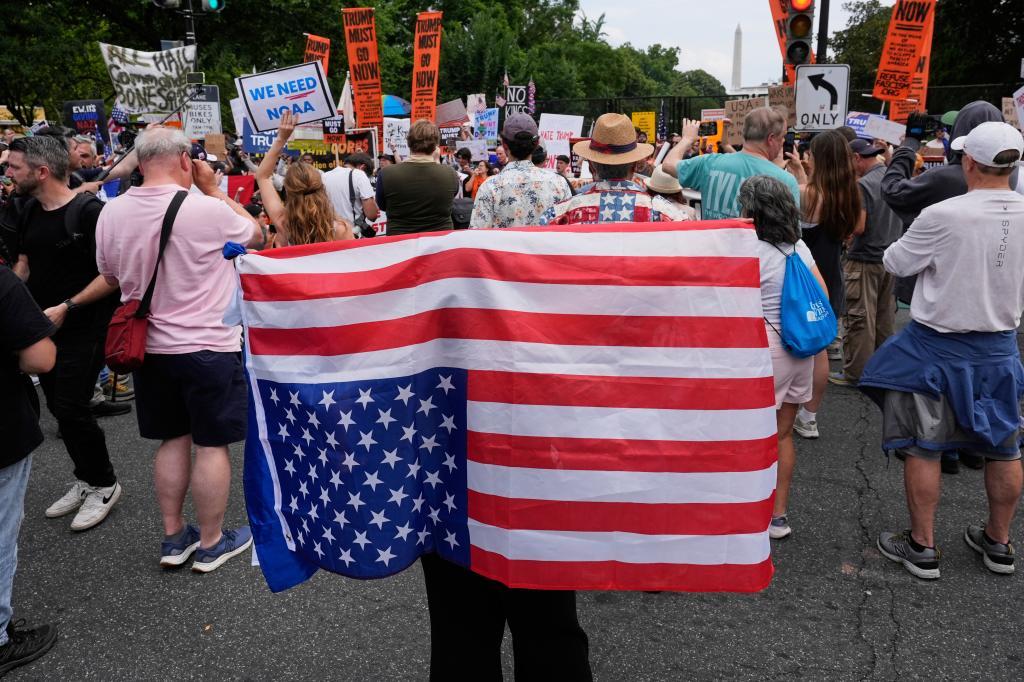 A person carries an American flag upside down during a protest near the White House