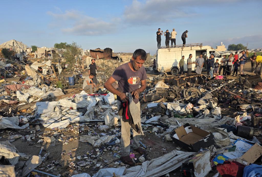 Palestinian displaced families inspect damage to their tents and belongings following an Israeli airstrike