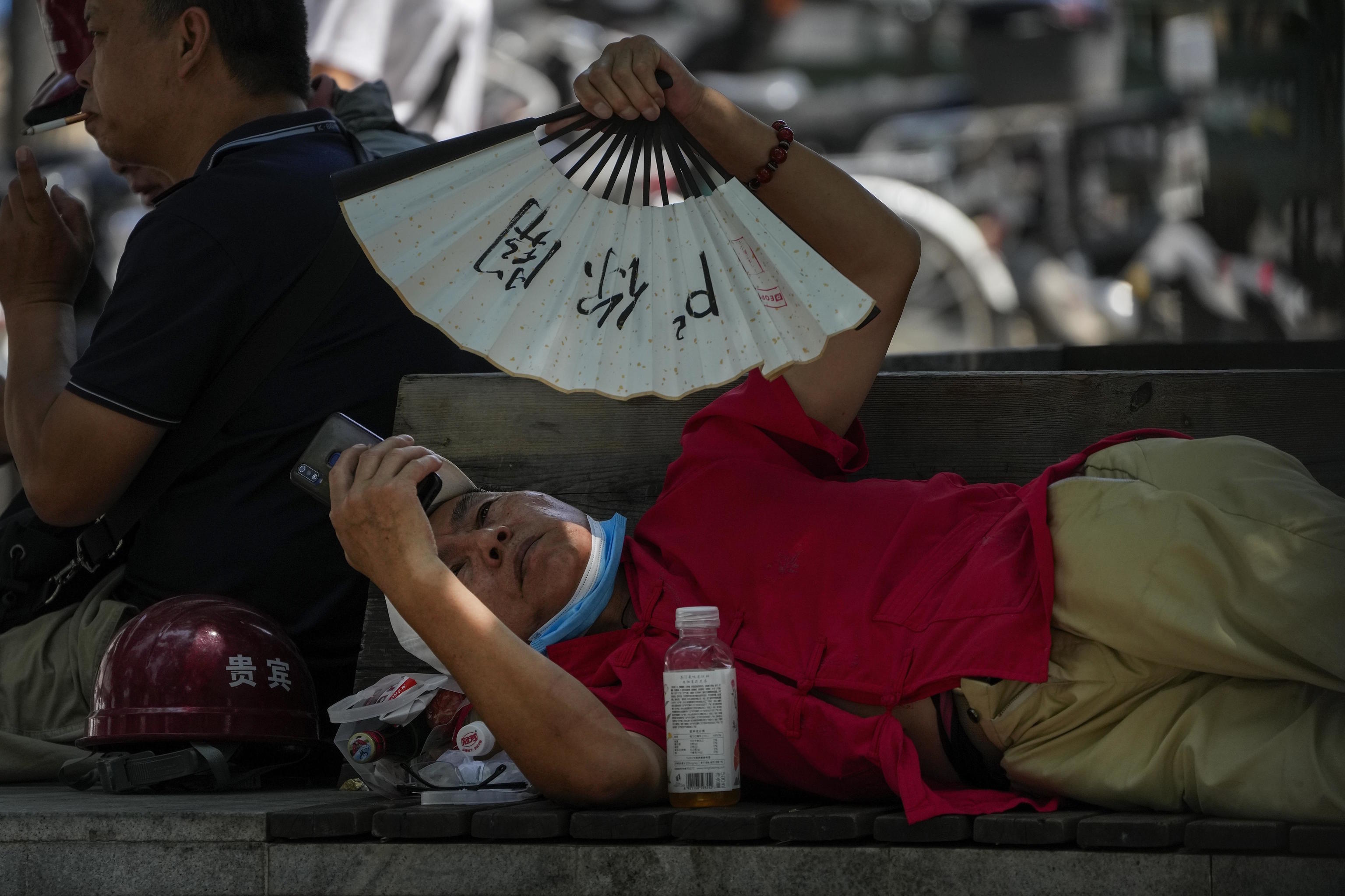 A man cools himself with a fan in Beijing.