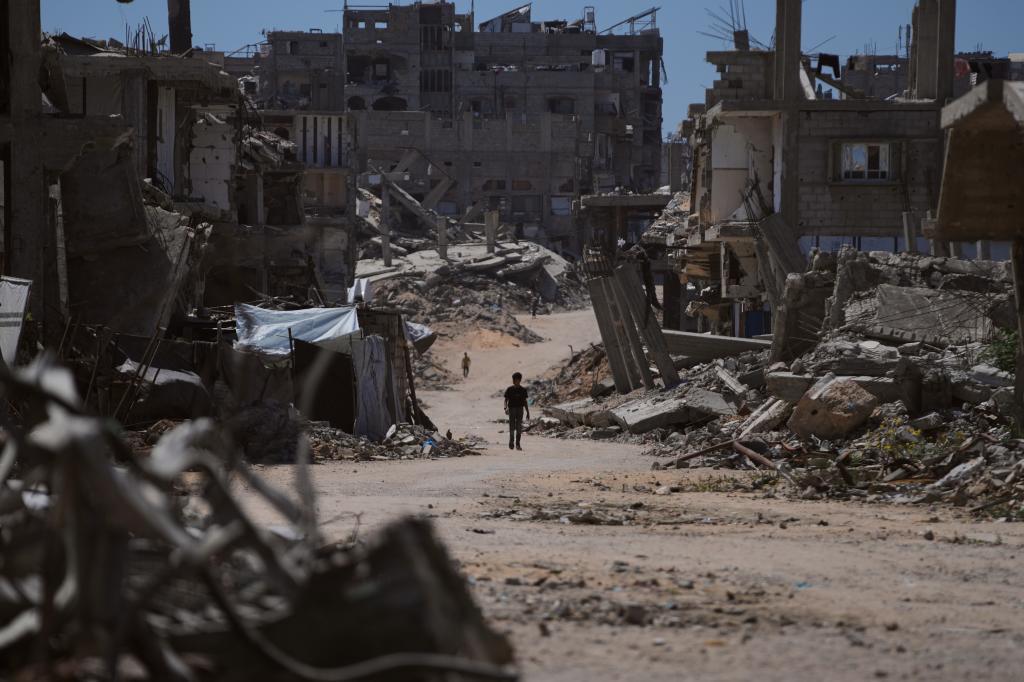A Palestinian boy walks down a street surrounded by buildings destroyed in Israeli military attacks during the war between Israel and Hamas.