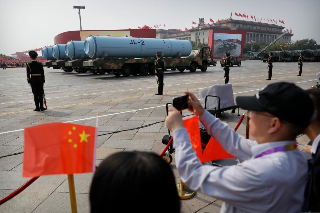Spectators wave Chinese flags as military vehicles carrying JL-2 submarine-launched missiles roll