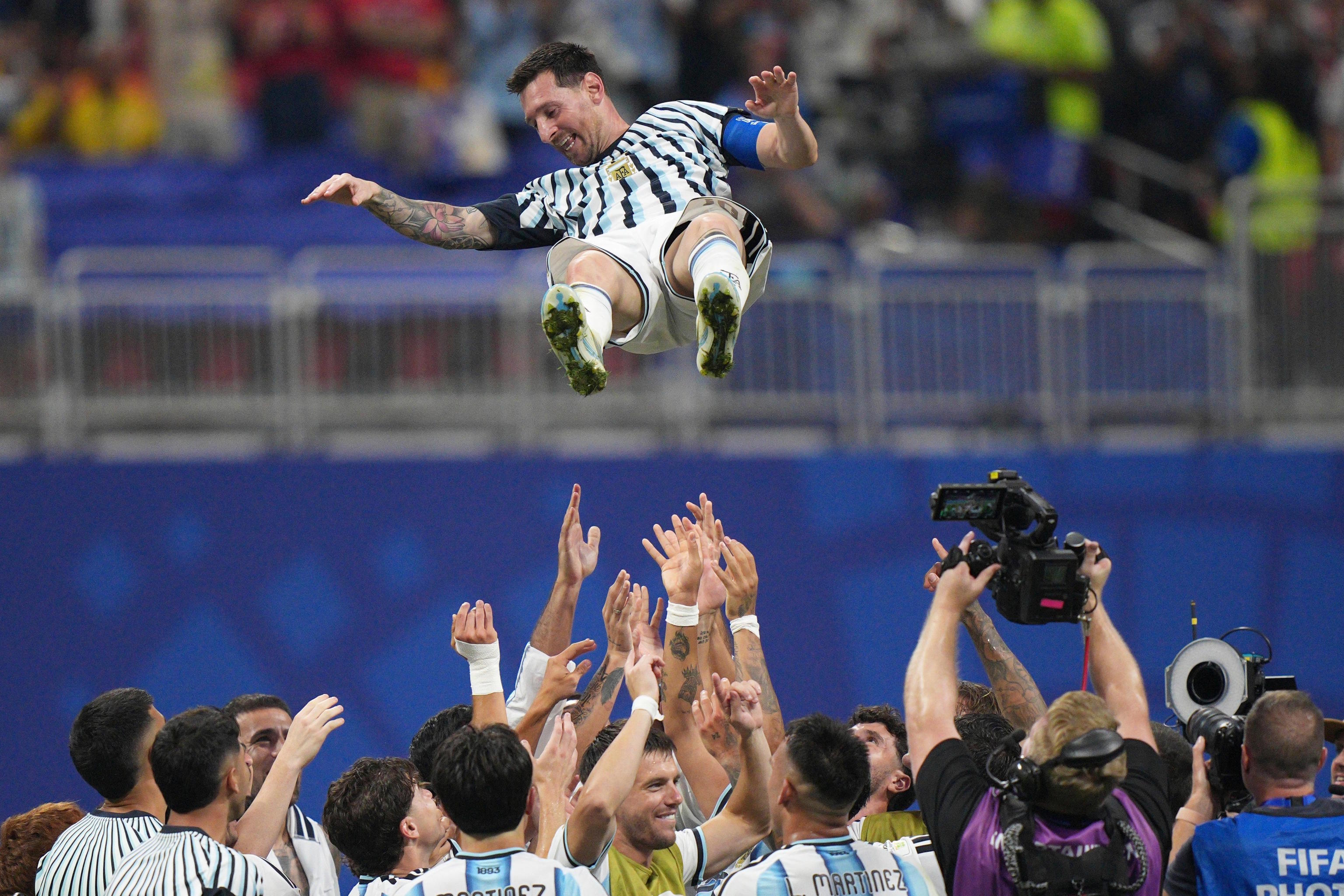 Argentina players toss teammate Messi into the air.
