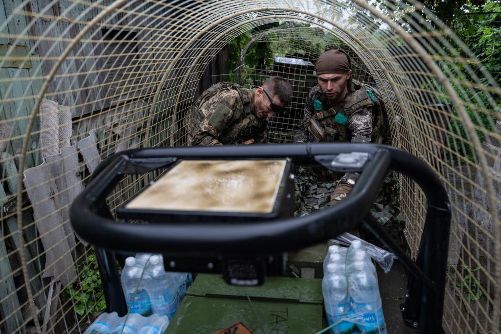 An Ukrainian serviceman unloads a ground drone that carries ammunition, water, and provisions in the frontline