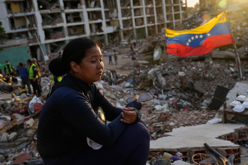 Estefany Landaez sits amid the rubble of a building, waiting to find her two children after the earthquakes in La Guaira, Venezuela