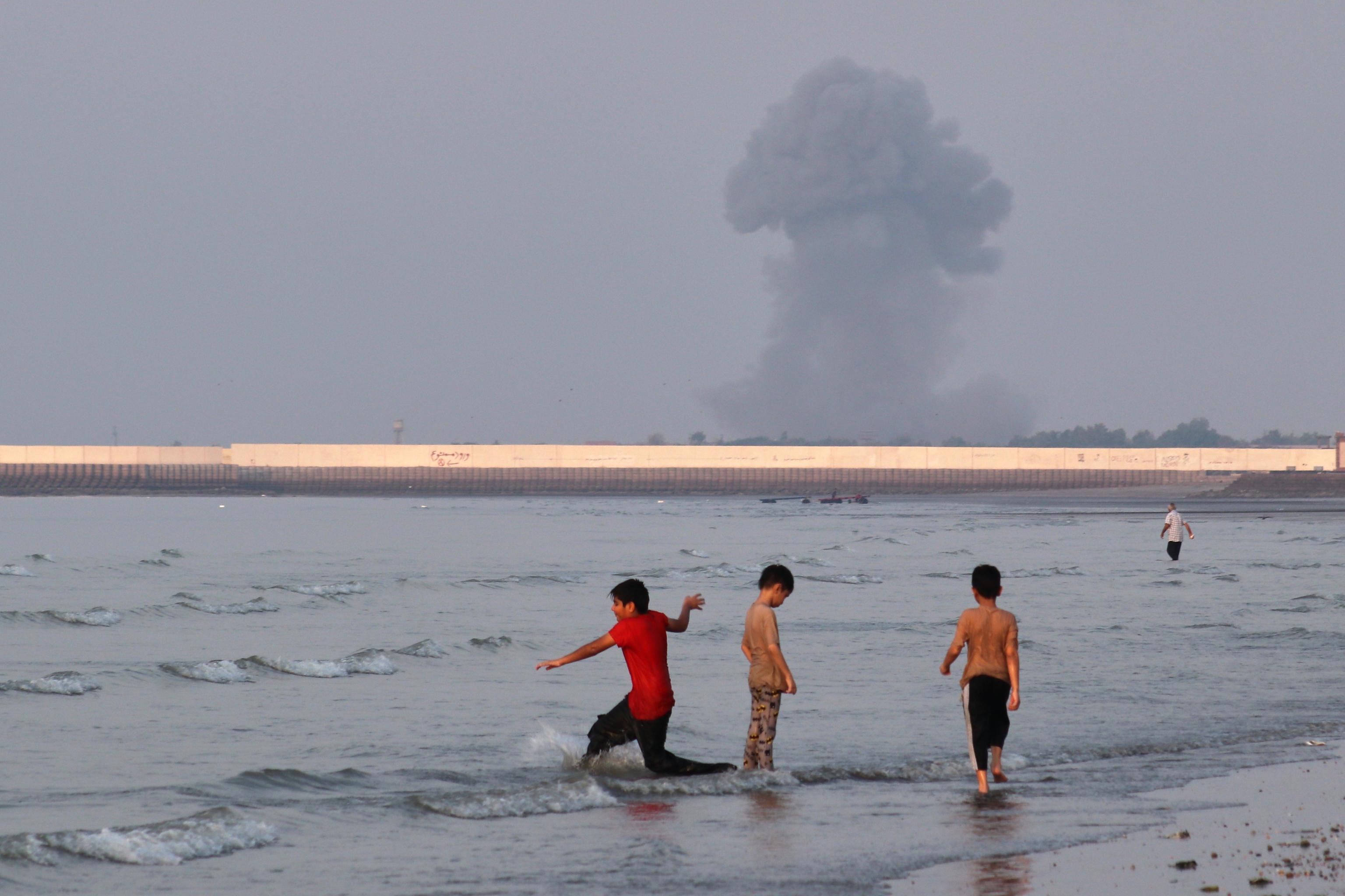 Three boys play in the shallow waters of the Strait of Hormuz.