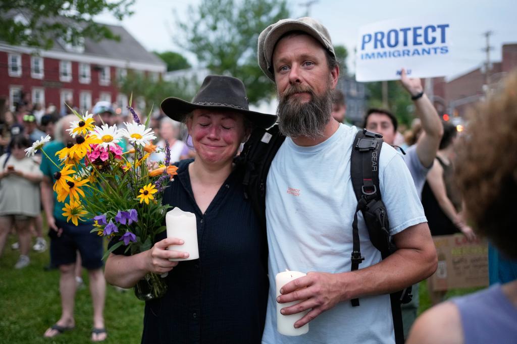 Attendees stand during a vigil after a man was shot and killed by U.S. Immigration and Customs Enforcement