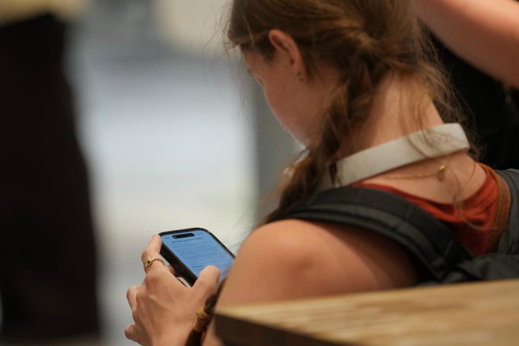 A teenager looks at her mobile phone in London.