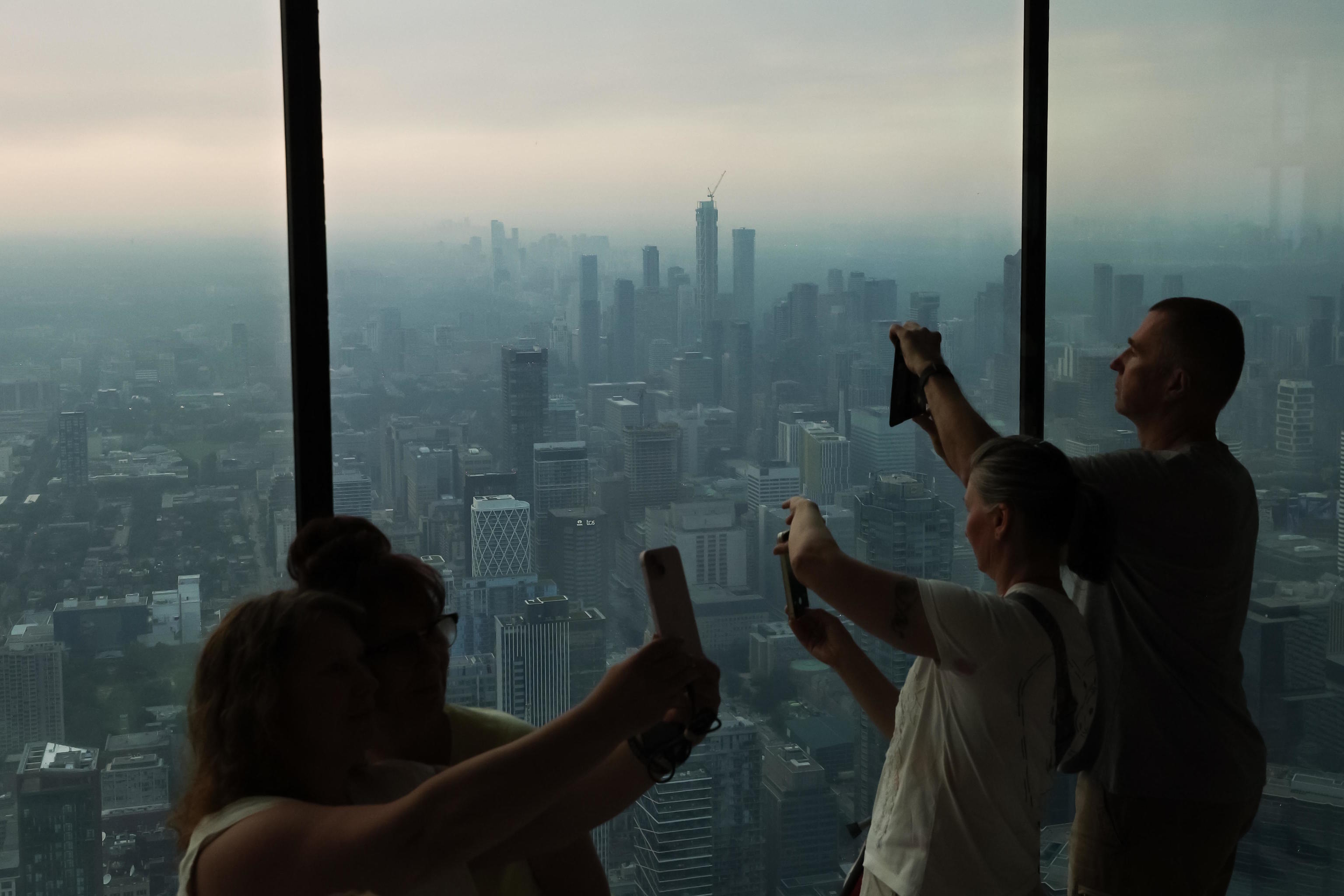 People take photos from deck of the CN Tower as smoke from wildfires  blankets the city of Toronto