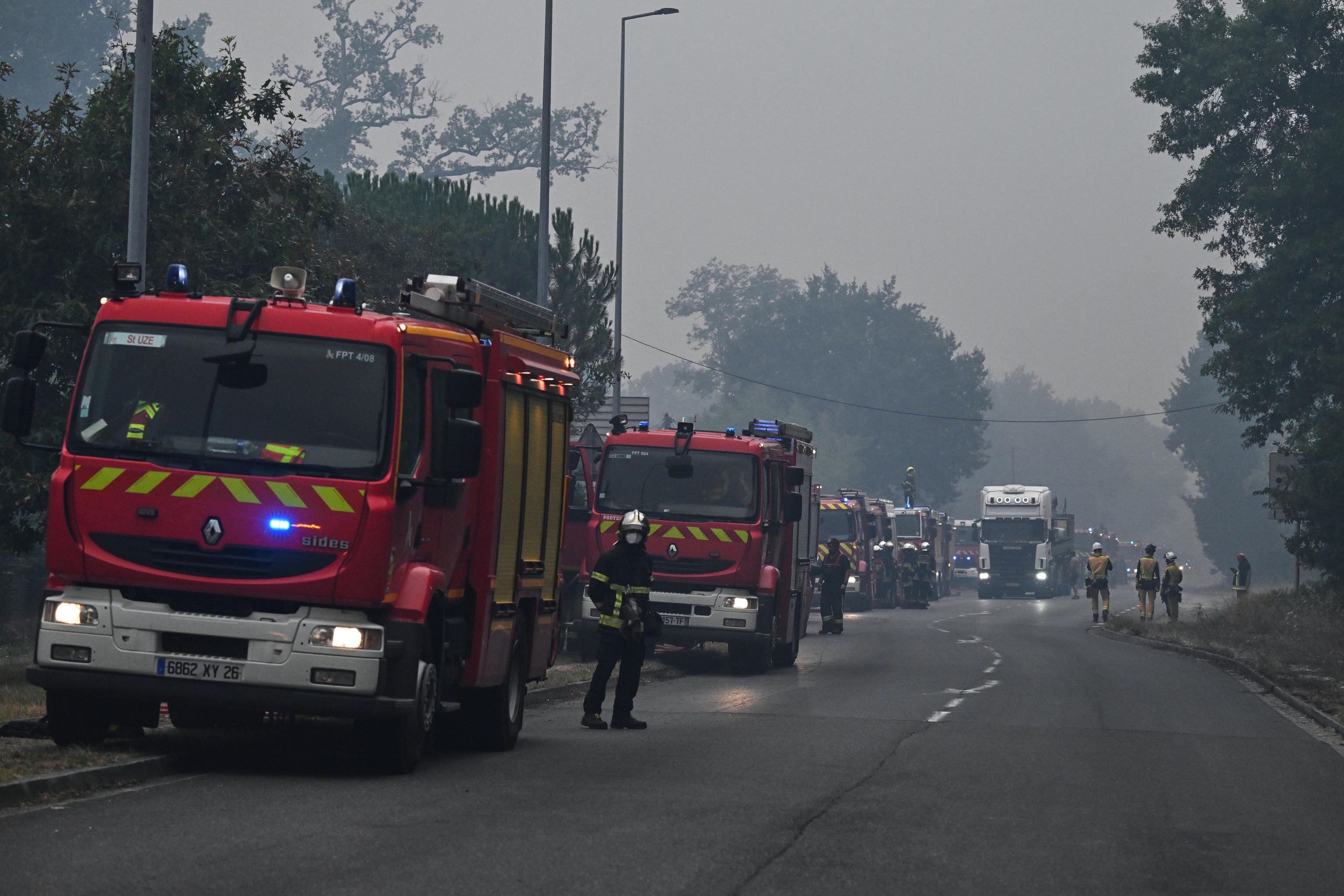 Fire engines parked along a road are enveloped in smoke from wildfires, near Marcheprime, outside, Bordeaux.