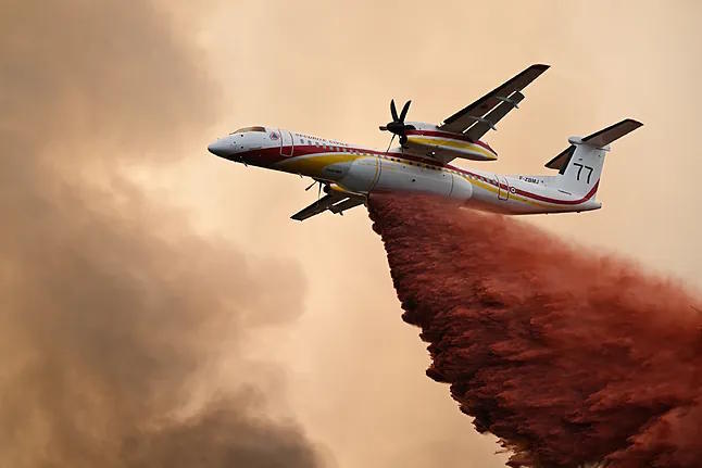 An airplane drops retardant over a forest during fires in France.