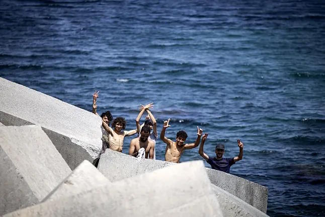 Moroccan migrants hide among the rocks near Trampolín beach in Ceuta.