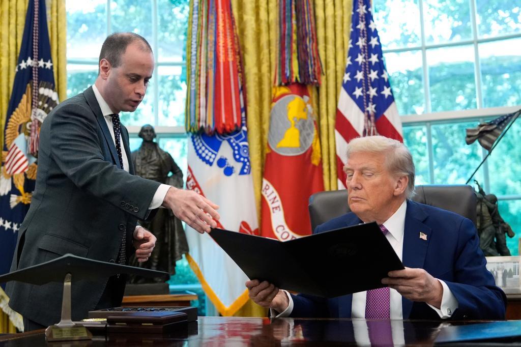 White House staff secretary Will Scharf, left, hands President Donald Trump