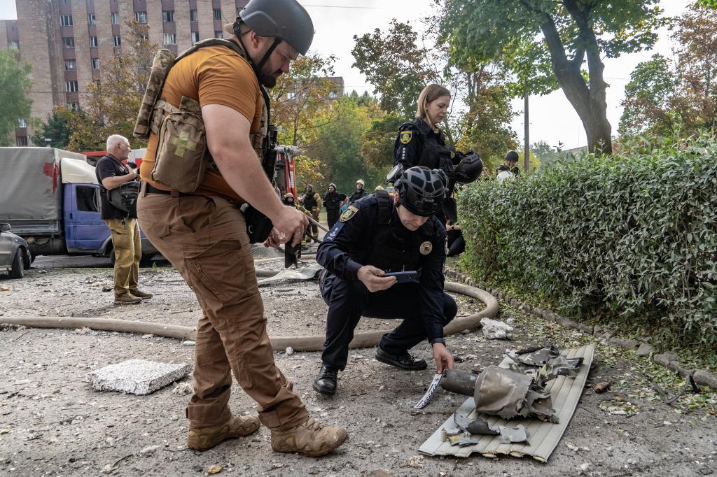 Police officers inspect fragments of a Russian drone after an air attack to a residential building in Kharkiv
