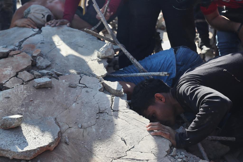 Residents and rescue workers search through the rubble of a building that collapsed after an earthquake