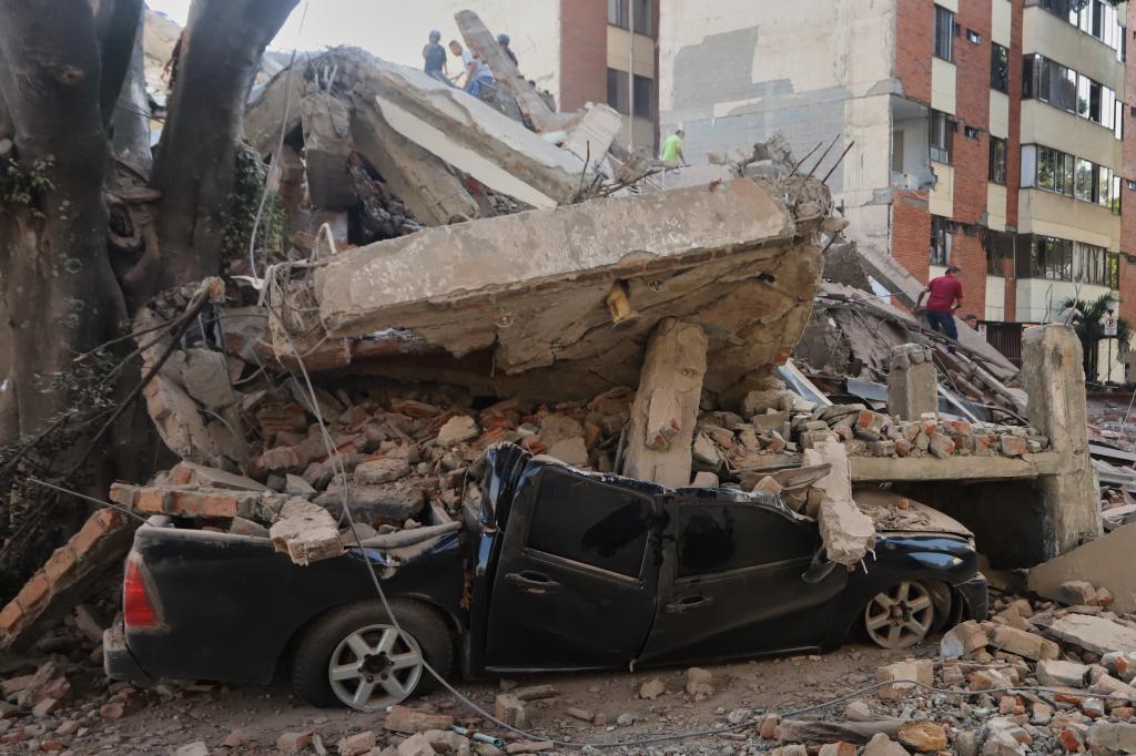 A vehicle lies crushed under debris following an earthquake